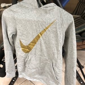 A grey Nike hoodie with a Nike sign in gold.
